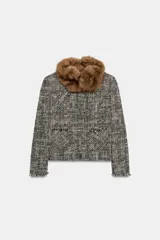 Chaqueta de tweed en tonos gris y negro, con cuello desmontable de pelo sintético marrón, bolsillos delanteros de plastrón y acabados deshilachados.