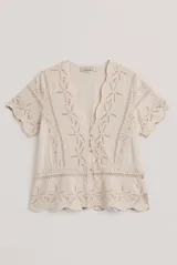 Camisa azul de manga corta confeccionada en tejido broderie con diseño calado y floral. Cuenta con escote en V y cierre frontal de botones.