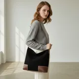 Bolso tipo hobo de eco cuero con textura símil gamuza color marrón rojizo. Presenta detalles de cuero liso color caramelo en la base y tiras ajustables en los laterales.