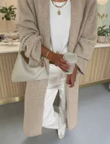 Cardigan largo de tejido de punto en color beige, con diseño de calce relajado y mangas amplias. Presenta un largo maxi y terminaciones acanaladas en los puños y el ruedo.