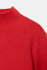 Jersey de punto liso en color gris, con cuello subido y mangas anchas de corte holgado. Presenta acabados en rib en el cuello y los puños.
