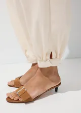 Pantalón jeans estilo balloon de tiro medio y largo tobillero, confeccionado en 100% algodón. Presenta detalle de pinzas en la cintura, dos bolsillos laterales, cierre de gancho y cremallera, y puños elásticos en los tobillos.