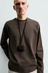 Camiseta de manga larga con corte relajado, confeccionada en tejido de algodón compacto. Presenta cuello redondo y detalle de costura en el centro de la espalda.