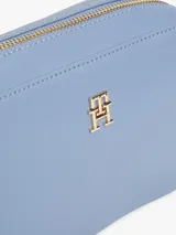 Bandolera Tommy Hilfiger azul con correa ajustable negra, cierre superior y logo dorado de la marca en el frente.
