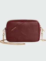 Cartera tipo crossbody Golden Goose, modelo Star Bag mini, color bordó. Confeccionada en cuero con textura granulada, presenta una estrella grande grabada en el frente y detalle de logo dorado. Incluye correa de cadena metálica dorada y cierre superior.