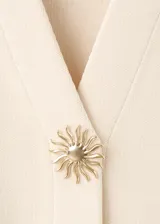Cardigan de punto fino color crudo, con cuello en V, mangas cortas y cierre frontal con un botón joya en forma de flor.