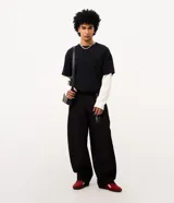 Pantalón masculino de sarga de algodón en color negro, con corte baggy balloon de piernas amplias y leve ajuste en los puños. Diseño de acabado liso, con amplios bolsillos delanteros y llavero removible en la cintura.