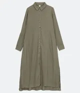 Vestido chemise largo color naranja, confeccionado en viscolino. Tiene cuello solapa, cierre con botones, manga larga con martingale, aberturas laterales y no tiene estampado.