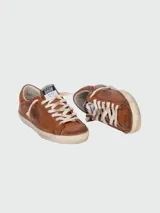 Zapatillas Golden Goose modelo Super-Star de cuero color marrón con efecto desgastado. Presentan cordones color crema, suela de goma envejecida y detalles de escritura grabada en el lateral y la puntera.