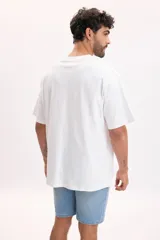 Remera oversize blanca de manga corta, con cuello redondo y estampa frontal de ilustraciones en tono azul con temática costera.