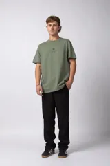 Remera de corte oversize color verde oliva, confeccionada en algodón premium. Presenta un diseño minimalista con un pequeño estampado frontal de un sol y el texto VCP Concept Studio, y una gráfica protagonista en la espalda.