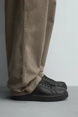 Zapatilla de cordones monocolor blanca, con parte superior fabricada en combinación de piezas, horma redonda y suela con volumen.