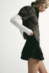 Falda corta de tiro bajo con diseño de volantes en el ruedo y detalle fruncido en la cintura. Confeccionada en tejido con efecto ante, cuenta con cierre lateral mediante cremallera oculta.