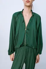 Pantalón de tiro medio confeccionado en tejido satinado verde, con diseño bombacho y bajos acabados en puño elástico. Cuenta con cierre lateral con cremallera oculta en costura.