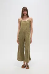 Mono de algodón color verde oliva, con textura plisada, escote en V y tirantes finos tipo lencero. Presenta bolsillos frontales y corte holgado.