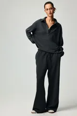 Buzo en tejido liviano color gris oscuro, con cuello camisero, tapeta de botones, hombros caídos y puños acanalados.