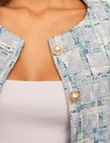 Chaqueta de tweed azul con cuello a la base, abertura central y bolsillos delanteros. Puños con aplique de botones perlados y forro interno.