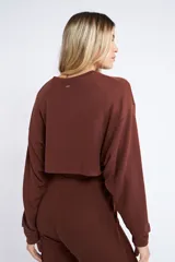 Buzo corto de tejido rib en color verde militar, con mangas largas y cuello redondo. Presenta un diseño holgado y cropped.