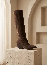 Bota de caña alta confeccionada en cuero vacuno color marrón, con taco cuadrado de 6 cm y suela de caucho antideslizante.
