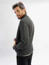 Campera tejida de punto en color beige, con diseño de trenzas y rombos, cuello alto y cierre frontal completo.