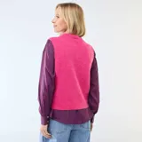 Chaleco sin mangas de punto suave en color fucsia, con escote en V y cierre frontal de botones blancos.