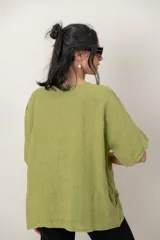Blusa de lino color blanco, de corte amplio, con escote redondo, mangas cortas y detalle de guarda calada horizontal en la parte inferior.