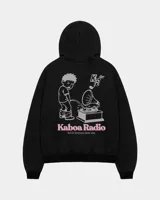 Canguro negro con capucha, de corte regular y confección en felpa suave, con estampa en la espalda de un personaje gráfico y texto "Kaboa Radio".