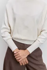 Sweater de punto color negro, con cuello alto y mangas largas de corte raglán.