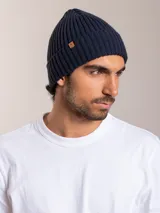 Gorro de lana azul marino con textura acanalada y etiqueta de cuero con logo de la marca en el lateral.