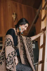 Ruana de algodón color beige con intervención de hilado de cuero de napa ovina color negro. Diseño artesanal con calados geométricos.