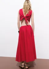 Falda larga color rojo, de tiro medio y diseño evasé, con bolsillos laterales y cierre de cremallera lateral.