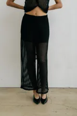 Pantalón largo de tejido de red negro, con forro interior opaco. Presenta un tiro alto y un calce ancho.