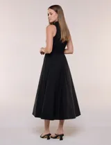 Vestido midi sin mangas de color verde militar, confeccionado con la parte superior en tejido de punto acanalado con cuello alto y falda acampanada de gran vuelo.