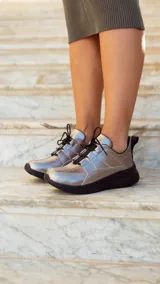 Championes deportivos de cuero en tonos marrón, tostado y marrón oscuro, con detalles de estampado animal print de leopardo en el lateral, suela gruesa blanca y cordones elásticos.