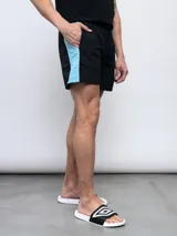 Short de baño negro con una franja vertical celeste con diseño estampado en el lateral.