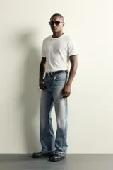 Jeans flare fit de denim de algodón en color celeste con lavado efecto desgastado. Presentan diseño de cinco bolsillos, tiro medio, cierre frontal con cremallera y botón, y bajo con acabado irregular.