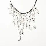 Collar con base de cordón negro y colgantes de flores blancas y cuentas blancas.