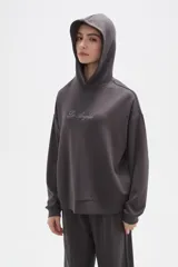 Canguro con capucha de calce holgado, color bordó, con detalle de aplique de strass en el pecho.