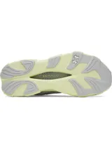 Championes deportivos blancos con detalles en gris claro y suela de color verde lima. Presentan un diseño de malla transpirable y una suela con tecnología HOVR+ para mayor amortiguación y retorno de energía.