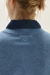 Sweater de punto color beige, con cuello redondo, manga larga y puños acanalados.