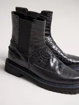 Bota tipo Chelsea de cuero con textura de reptil, color suela, con paneles elásticos laterales negros y suela de goma dentada con pespuntes en contraste.