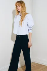 Jean de tiro alto y pierna ancha en denim de algodón negro, con diseño clásico de cinco bolsillos, cierre de cremallera y botón metálico.