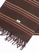 Bufanda de tejido suave en color marrón chocolate con diseño de rayas horizontales en tonos naranja, beige y gris. Presenta terminaciones con flecos en los extremos.