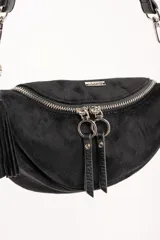 Cartera tipo bandolera de tamaño pequeño, confeccionada en material sintético con textura de gamuza en color marrón topo. Presenta un diseño semicircular con cierre superior, herrajes metálicos plateados y una correa larga ajustable de cinta técnica.