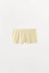 Shorts de tiro medio de tejido pointelle color beige, con cintura elástica y detalle de aplicación de encaje a tono en el ruedo.