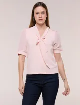 Blusa de modal y gasa color rosado, con escote en V y detalle de lazo en el cuello. Mangas cortas translúcidas con puños elastizados.
