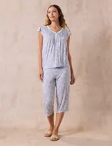 Conjunto de pijama marca René Rofé, compuesto por una remera de escote en V con botones y un pantalón capri con cintura elastizada, ambos en tejido soft estampado con motivos florales en tonos celeste y blanco.