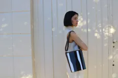 Matera de cuero con diseño de paneles verticales en combinación de colores azul, verde, marrón y bordó. Cuenta con dos asas cortas de cuero y estructura rígida.