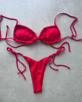 Conjunto de bikini rojo con corpiño triangular con lazos y bombacha semi vedetina con tiras ajustables.