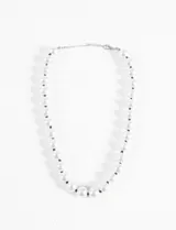 Collar corto de perlas blancas de acrílico con hilo de nylon negro entre cada perla y cadena plateada con cierre de mosquetón.